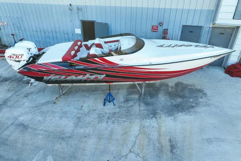  Yacht Photos Pics 2022 Velocity 290sc speedboat with red and black design, parked on concrete.