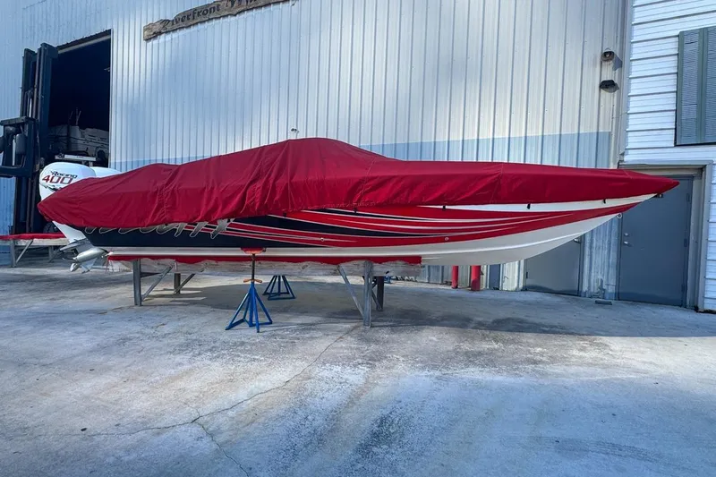  Yacht Photos Pics 2022 Velocity 290sc boat covered in red tarp, stored on stands outside a building.