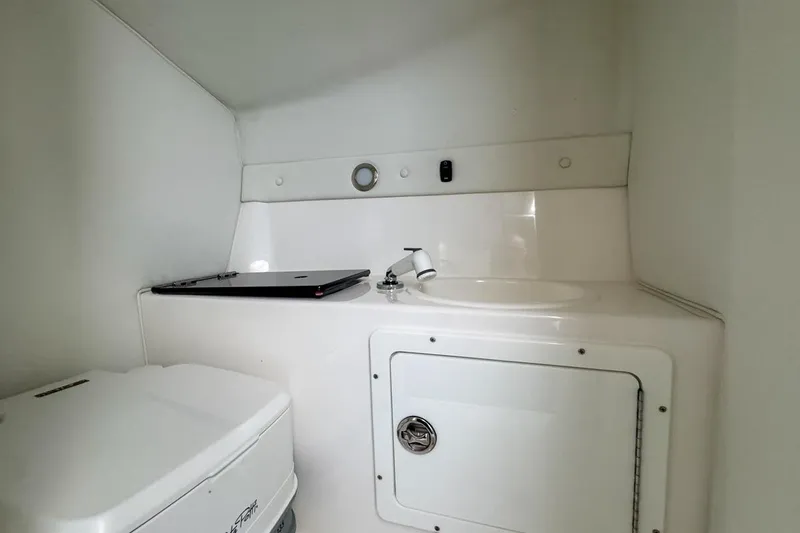  Yacht Photos Pics 2022 Velocity 290sc boat interior with compact bathroom and sink area.