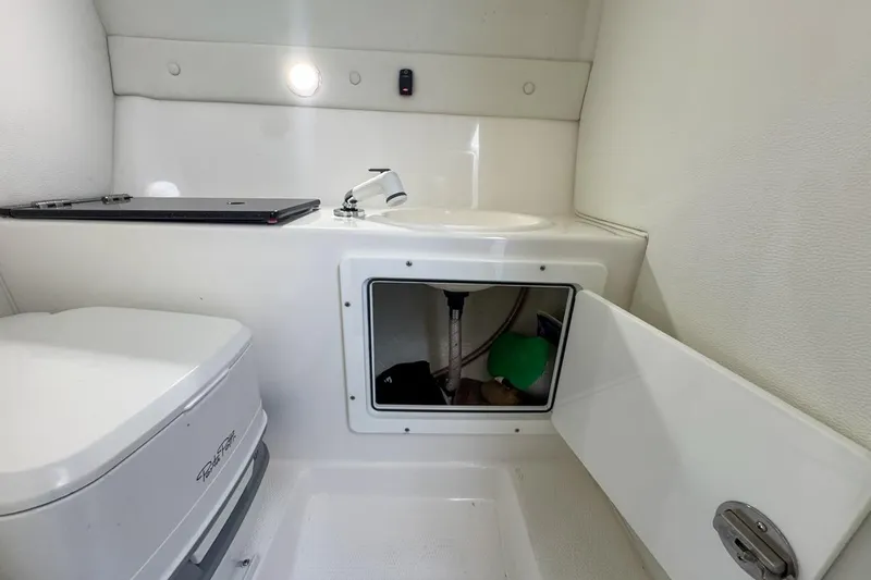  Yacht Photos Pics 2022 Velocity 290sc boat interior with compact bathroom and storage compartment.