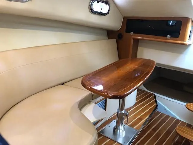 Good Fun Yacht Photos Pics 2006 Pursuit 3370 Offshore cabin interior with wooden table and beige seating.
