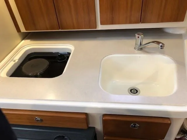 Good Fun Yacht Photos Pics 2006 Pursuit 3370 Offshore boat kitchen with sink and stove, wooden cabinets.
