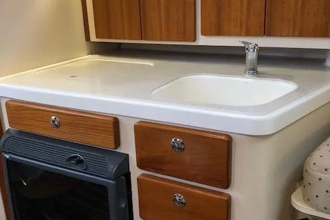 Good Fun Yacht Photos Pics 2006 Pursuit 3370 Offshore kitchen with sink, stove, and wooden cabinets.