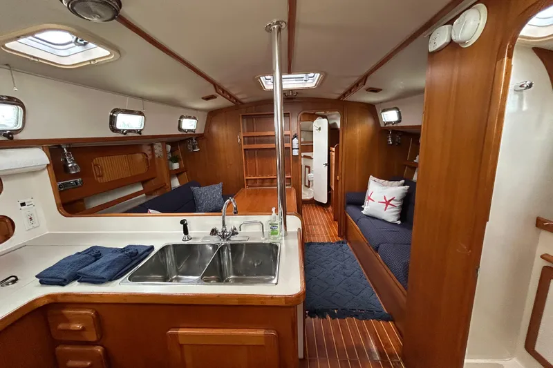 Harriet Tubman Yacht Photos Pics Interior of 2002 Caliber 40 sailboat with wood finish, kitchen, and seating area.