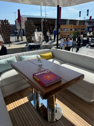  Yacht Photos Pics Luxury seating area on 2025 Azimut Magellano 66 yacht, featuring a wooden table and modern decor.