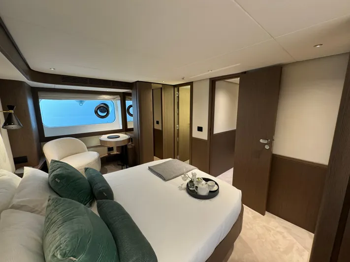  Yacht Photos Pics Luxurious bedroom interior of 2025 Azimut Magellano 66 yacht with elegant furnishings and porthole windows.