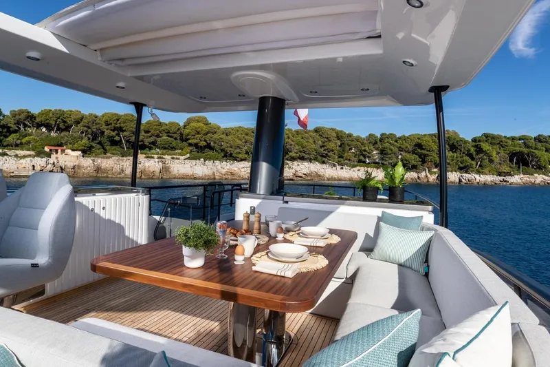  Yacht Photos Pics Luxurious 2025 Azimut Magellano 66 yacht deck with elegant dining setup and scenic ocean view.