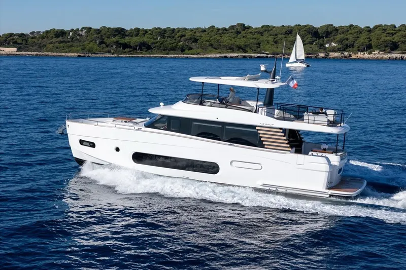  Yacht Photos Pics 2025 Azimut Magellano 66 yacht cruising on blue ocean near lush coastline.