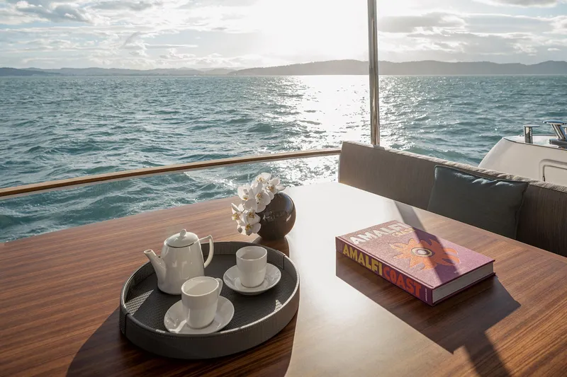  Yacht Photos Pics Luxurious Azimut Magellano 66 yacht interior with tea set and book, overlooking serene ocean view.