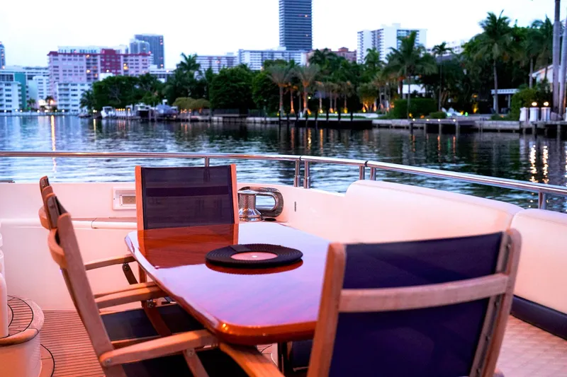 Kristina Yacht Photos Pics Luxury yacht deck with dining area, overlooking waterfront cityscape at dusk. Princess 23M, 2007 model.