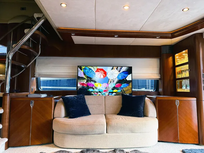 Kristina Yacht Photos Pics Luxurious yacht interior with beige sofa, colorful TV display, and elegant wooden cabinetry. Princess 23M, 2007.