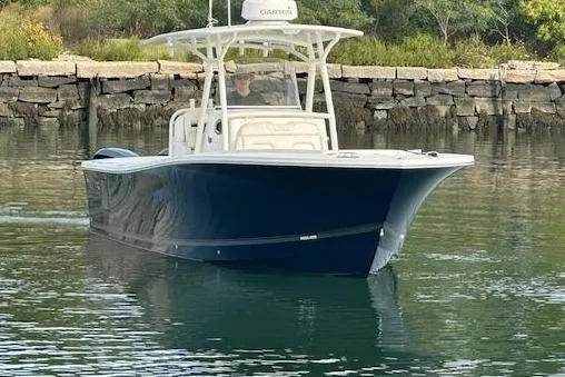 Resolute Yacht Photos Pics 2017 Regulator 31 boat cruising on calm water near a rocky shoreline.