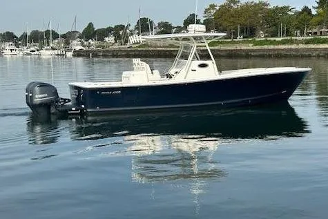 Resolute Yacht Photos Pics 2017 Regulator 31 boat on calm water near a marina and buildings.