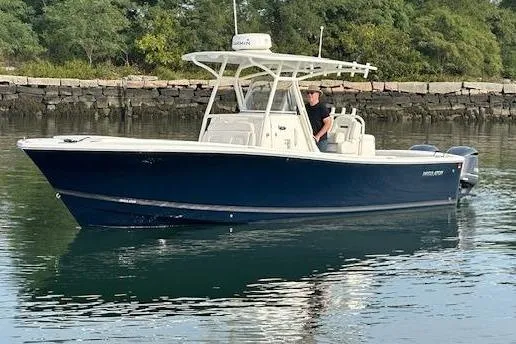 Resolute Yacht Photos Pics 2017 Regulator 31 boat on calm water near a rocky shoreline.