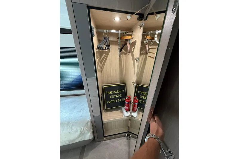Svetlana Yacht Photos Pics 2025 Sunseeker 76 Yacht interior closet with emergency escape hatch and fire extinguishers.