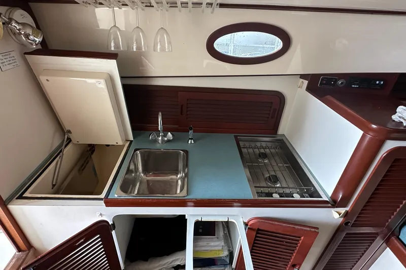 Stardust Yacht Photos Pics 1996 Hinckley Picnic Boat interior kitchen with sink, stove, and storage cabinets.