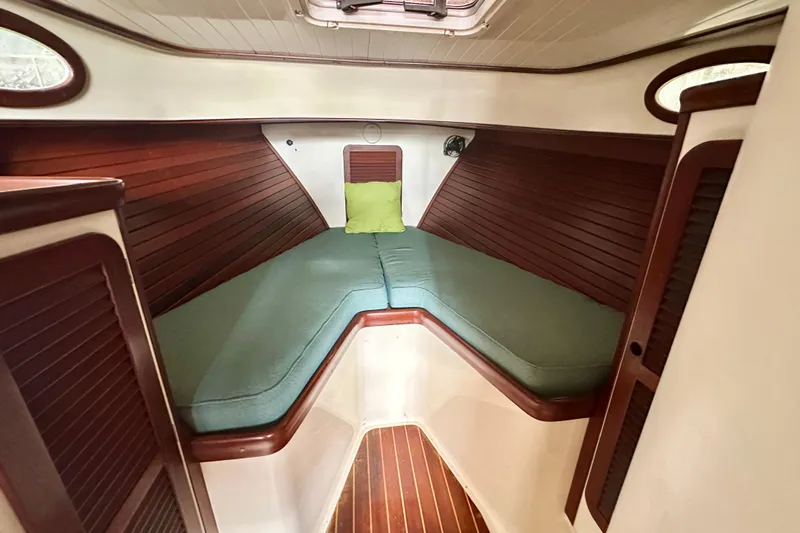 Stardust Yacht Photos Pics Interior of a 1996 Hinckley Picnic Boat with green cushions and wooden paneling.