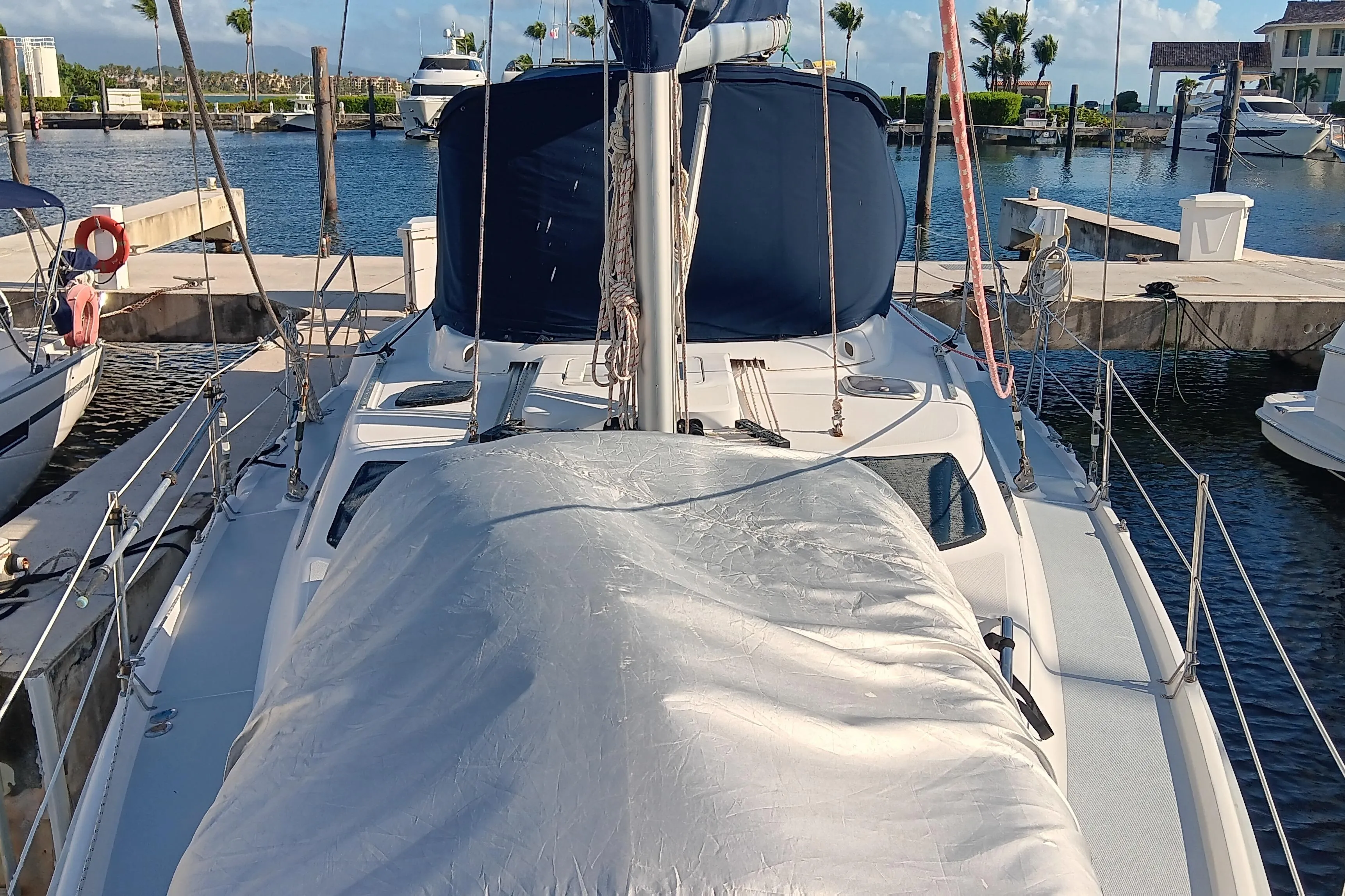 Sailboat docked at marina, Hunter 450 model, 1998, with covered deck and blue canopy.