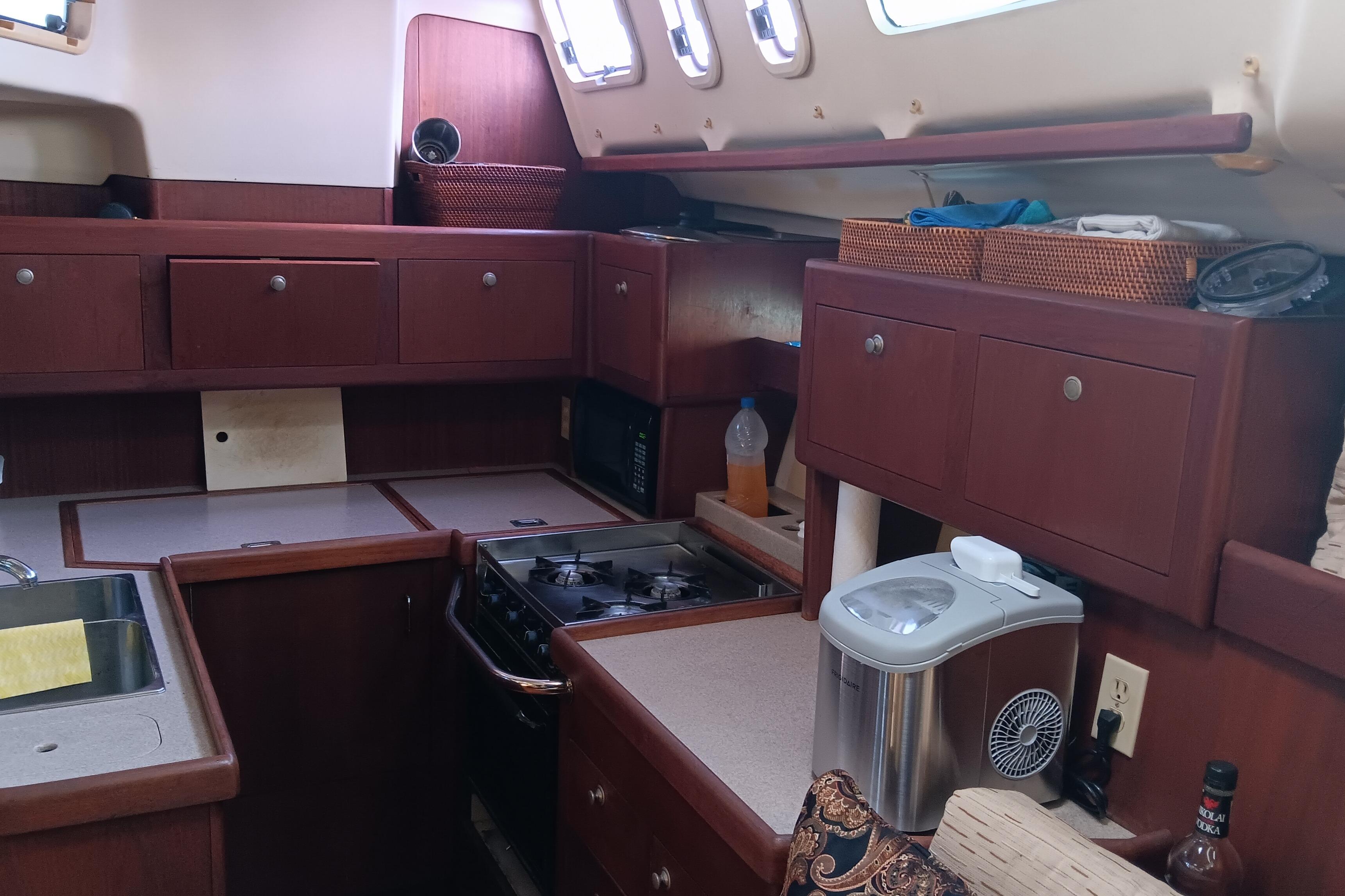 Interior of a 1998 Hunter 450 yacht kitchen with wooden cabinets and appliances.