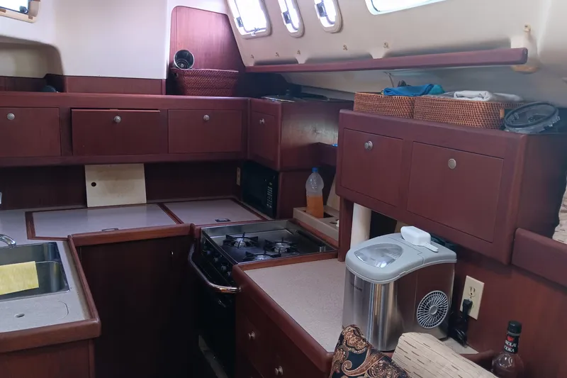 Heart Of Gold Yacht Photos Pics Interior of a 1998 Hunter 450 yacht kitchen with wooden cabinets and appliances.