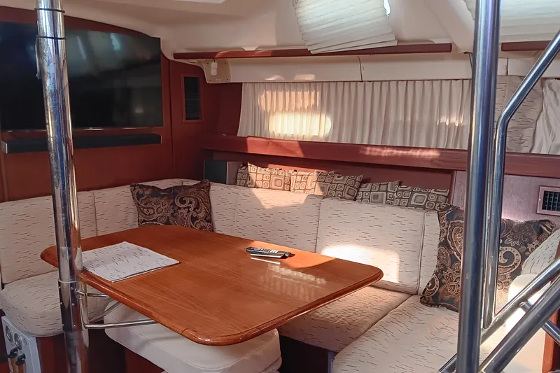 Heart Of Gold Yacht Photos Pics Cozy interior of 1998 Hunter 450 yacht with cushioned seating and wooden table.