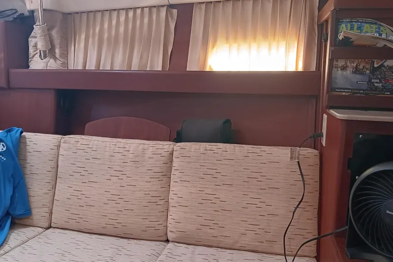 Heart Of Gold Yacht Photos Pics Interior of a 1998 Hunter 450 yacht with beige sofa and curtains.