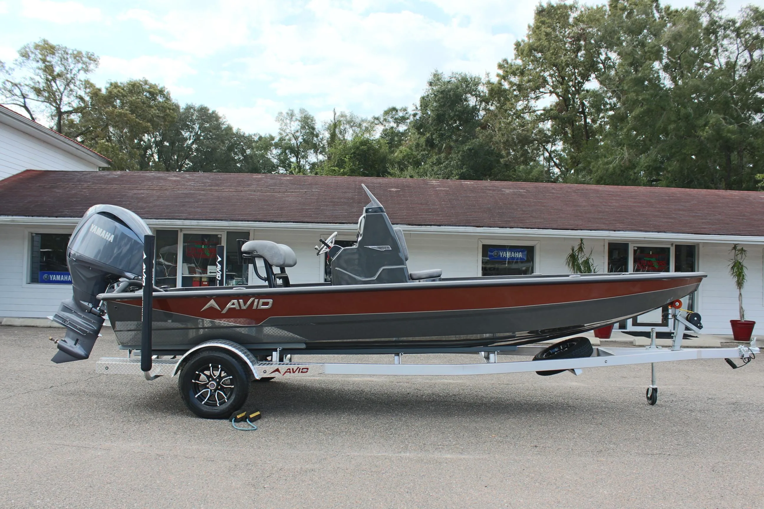 2025 Avid 21 FSX boat on trailer, parked outside a building.