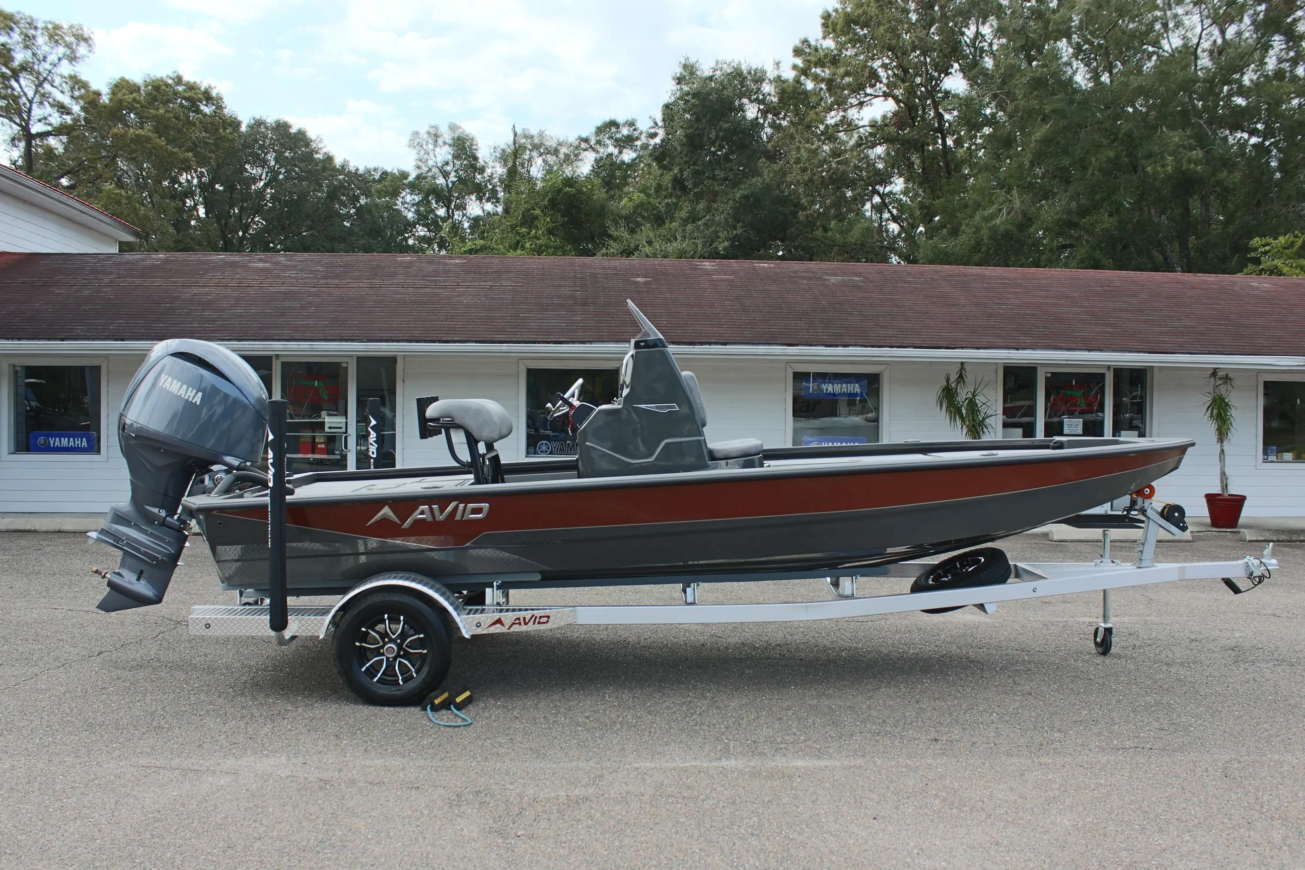2025 Avid 21 FSX boat on trailer, parked outside a building.
