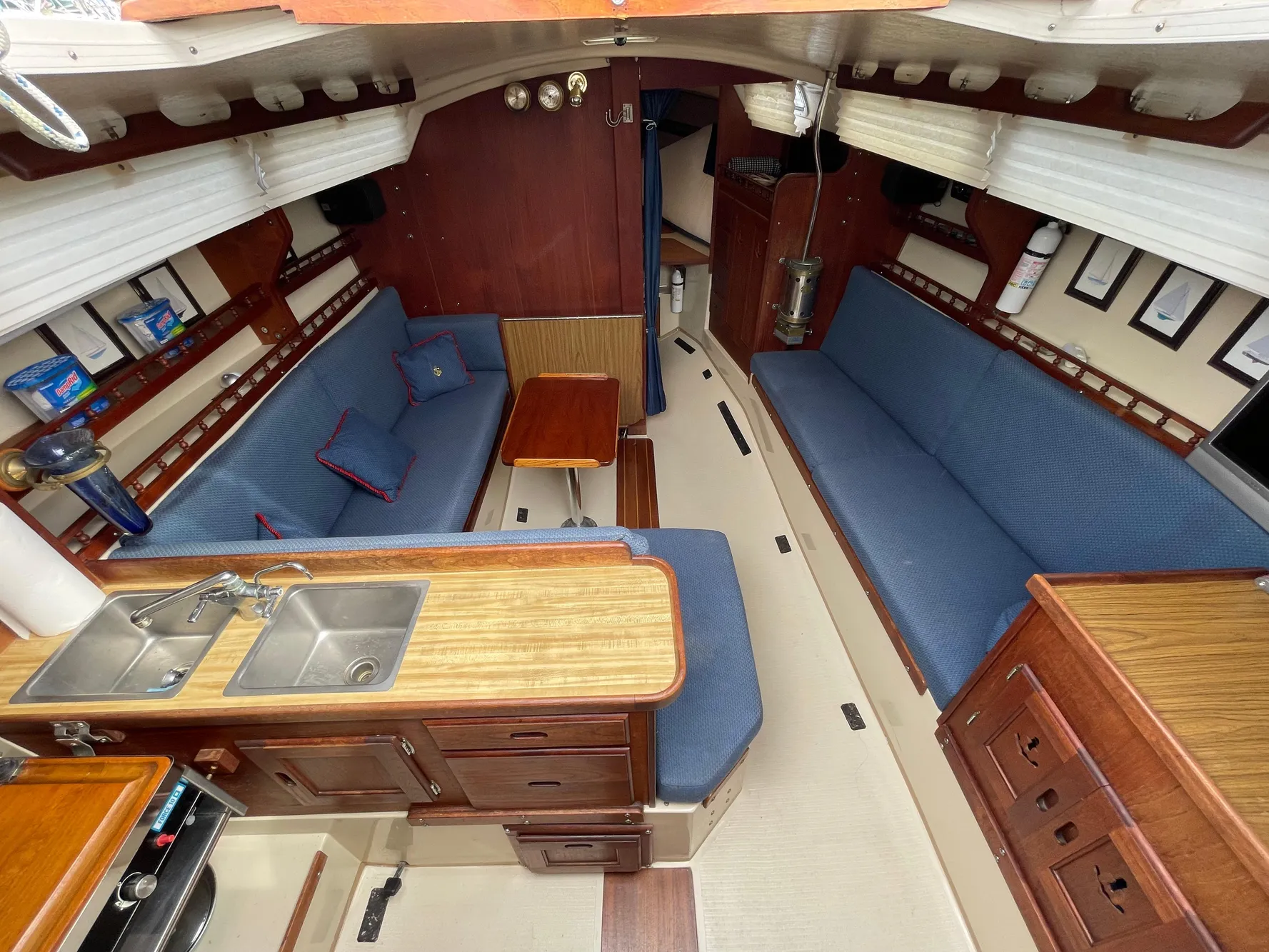 Interior of a 1984 Catalina 30 sailboat with blue seating and wooden cabinetry.