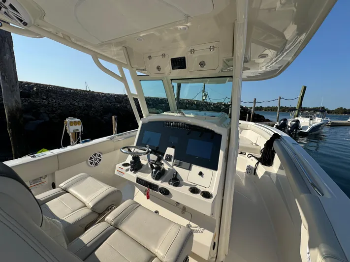  Yacht Photos Pics 2023 Sailfish 312 CC boat interior with modern dashboard and seating at a marina.
