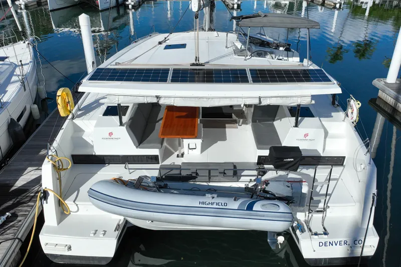 Firefly Yacht Photos Pics 2023 Fountaine Pajot Isla 40 catamaran with solar panels and dinghy, docked in a marina.