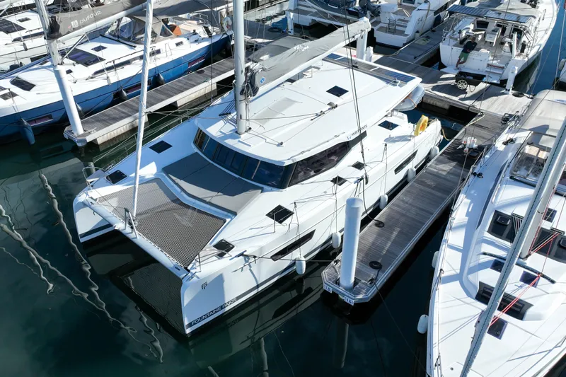 Firefly Yacht Photos Pics 2023 Fountaine Pajot Isla 40 catamaran docked at a marina, surrounded by other boats.
