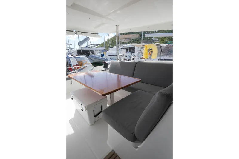Firefly Yacht Photos Pics Outdoor seating area on 2023 Fountaine Pajot Isla 40 catamaran with table and cushioned bench.