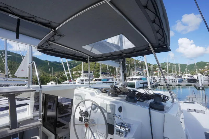Firefly Yacht Photos Pics 2023 Fountaine Pajot Isla 40 catamaran docked in a scenic marina with lush hills.