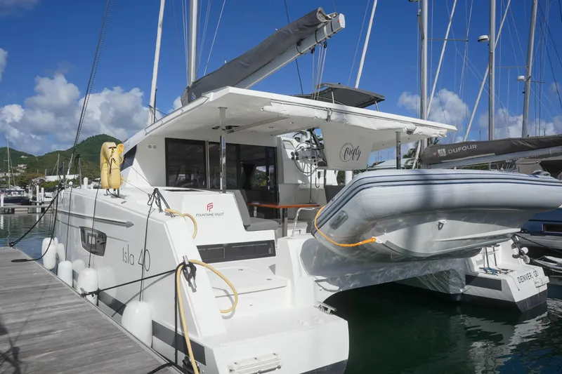 Firefly Yacht Photos Pics 2023 Fountaine Pajot Isla 40 catamaran docked at marina, featuring inflatable dinghy.
