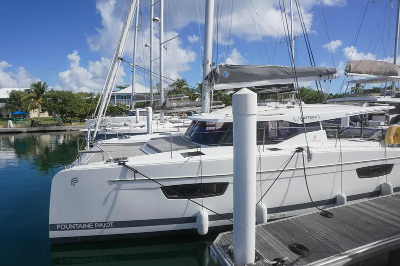 Firefly Yacht Photos Pics 2023 Fountaine Pajot Isla 40 catamaran docked in a marina under clear blue skies.