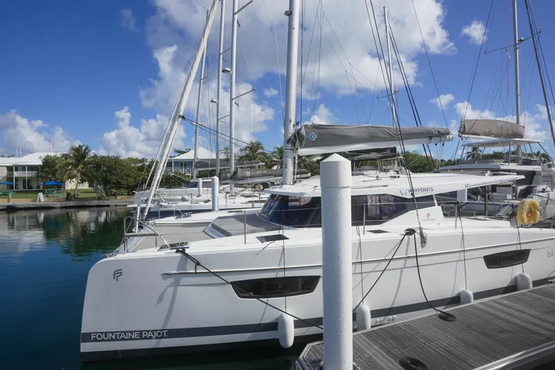 Firefly Yacht Photos Pics 2023 Fountaine Pajot Isla 40 catamaran docked at marina under blue sky.