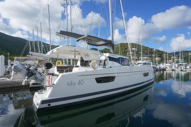 Firefly Yacht Photos Pics 2023 Fountaine Pajot Isla 40 catamaran docked in a scenic marina.