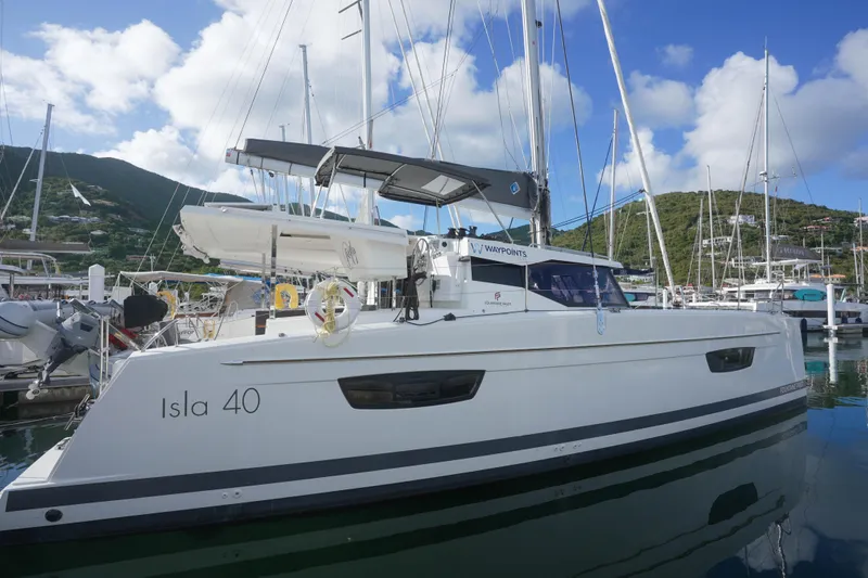 Firefly Yacht Photos Pics 2023 Fountaine Pajot Isla 40 catamaran docked in a marina, clear sky background.