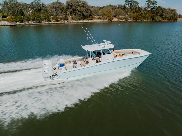  Yacht Photos Pics 2025 Freeman 38 boat cruising on a serene lake with lush trees in the background.