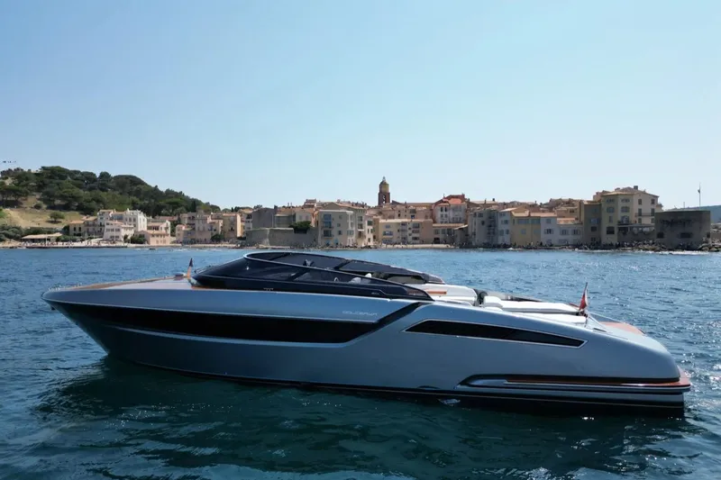  Yacht Photos Pics 2021 Riva Dolceriva luxury yacht on serene coastal waters with scenic town backdrop.