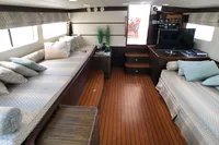 Luxurious interior of a 1991 Custom 23m Epoxy Hull yacht with cozy seating and wood flooring.