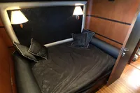 Luxurious cabin interior with black bedding, wooden walls, and soft lighting on a 1991 Custom 23m Epoxy Hull.
