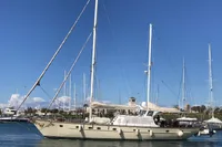 Sailing yacht with custom 23m epoxy hull, 1991 model, docked in a marina under clear blue sky.