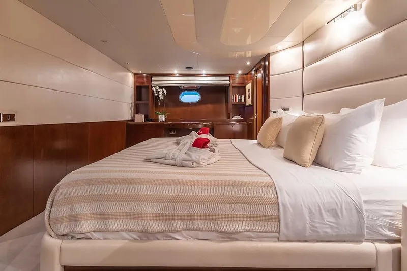 Let It Be Yacht Photos Pics Luxurious bedroom interior on 1998 Tecnomarine Custom yacht, featuring elegant bedding and wood accents.
