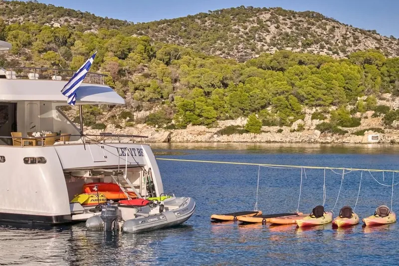 Let It Be Yacht Photos Pics Luxury Tecnomarine Custom yacht from 1998 docked with kayaks, scenic coastal backdrop.