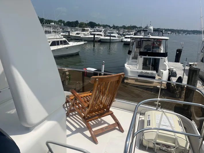 C Glass Yacht Photos Pics Wooden chair on Princess 65 M/Y yacht deck, overlooking marina with boats.