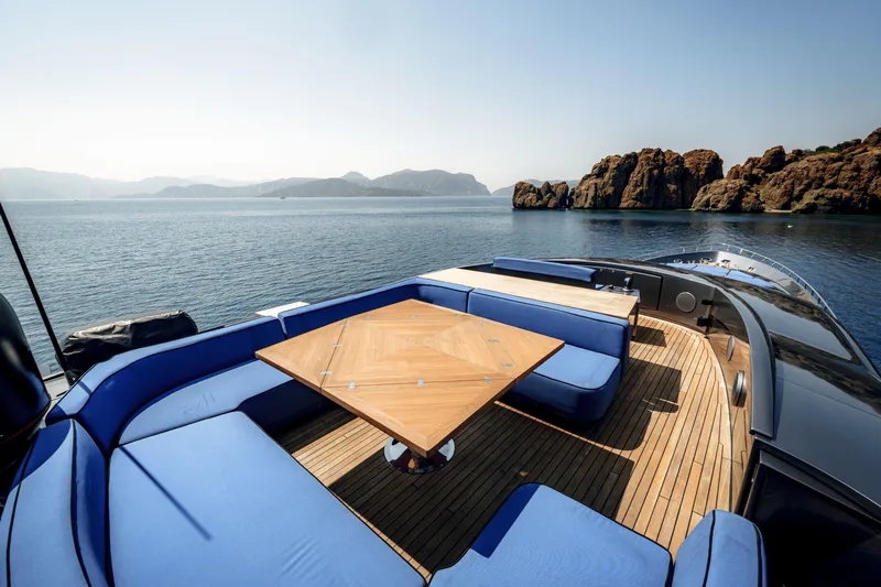 Ginger Yacht Photos Pics Luxury Pershing 115 yacht deck with blue seating, wooden table, scenic ocean view.
