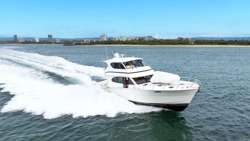 Unchained Freedom Yacht Photos Pics 2007 Maritimo M60 Cruising Motor Yacht speeding on open water, with city skyline in background.