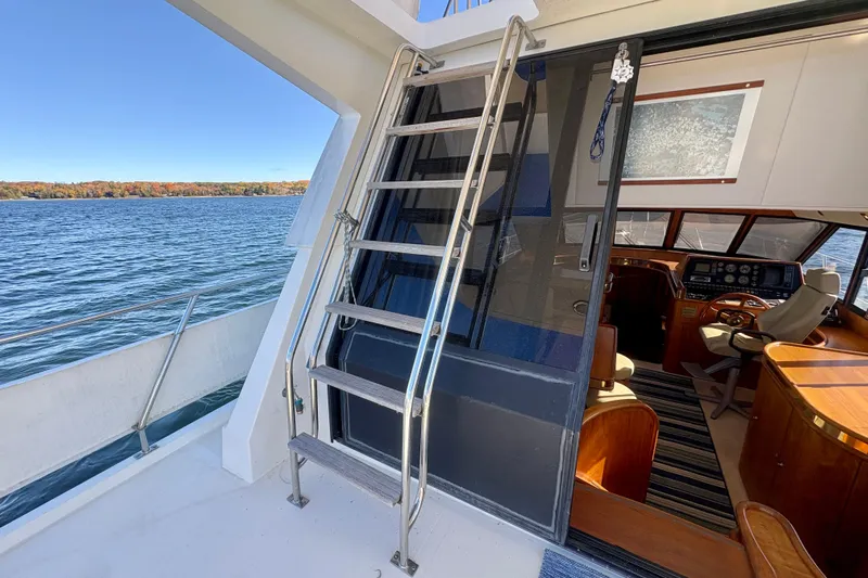 Kronberg Yacht Photos Pics 1990 Neptunus 145 AC yacht interior with helm, overlooking serene lake and autumn foliage.